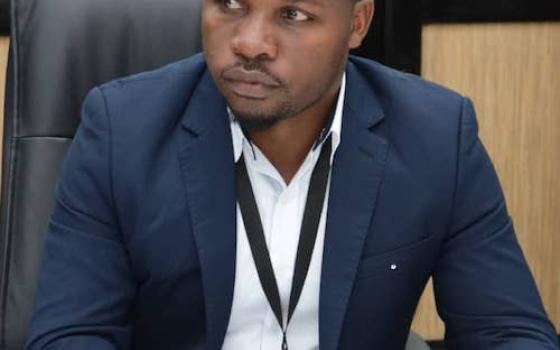 Boniface Chibwana, coordinator for the Catholic Commission for Justice and Peace of Malawi's bishop's conference sitting at desk