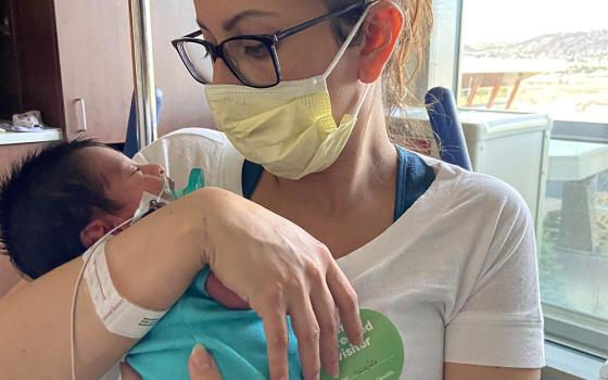 Estefanía Madrigal sits in a wheelchair propped up after her surgery, holding baby Oliver in the neonatal intensive care unit in April 2020 in Lonetree, Colorado. (Courtesy of Estefanía Madrigal)