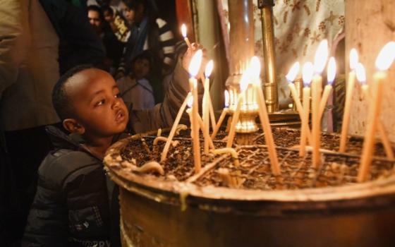 An Ethiopian boy lights a candle in the grotto in the Church of Nativity in Bethlehem, West Bank, Dec. 15, 2018. The church is built on the site believed to be where Jesus was born. (CNS/Debbie Hill)