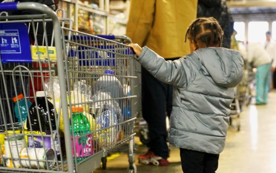 A young girl helps guide a shopping cart Nov. 15 through the food pantry operated by the Indianapolis Council of the Society of St. Vincent de Paul. The Catholic-run pantry serves about 3,000 local families each week. (CNS/Katie Rutter) 