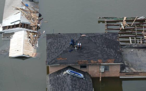 People sit on a roof waiting to be rescued after Hurricane Katrina struk New Orleans in August 2005. (Wikimedia Commons/Jocelyn Augustino/FEMA)