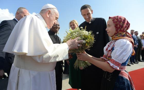 Pope Francis accepts flowers as he is welcomed by Slovak President Zuzana Caputová at the international airport in Bratislava, Slovakia, Sept. 12, 2021.