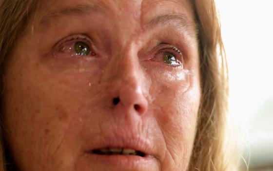 Sheryl Turner, who had trouble evacuating because she did not have fuel, becomes overwhelmed at the enormity of the bush fires last month at the evacuation center in Bomaderry, Australia. (CNS photo/Tracey Nearmy, Reuters)