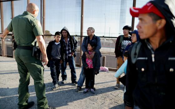 A group of Central American migrants is questioned about their children's health after surrendering to U.S. Border Patrol agents south of the U.S.-Mexico border fence in El Paso, Texas, March 6. (CNS/Reuters/Lucy Nicholson)