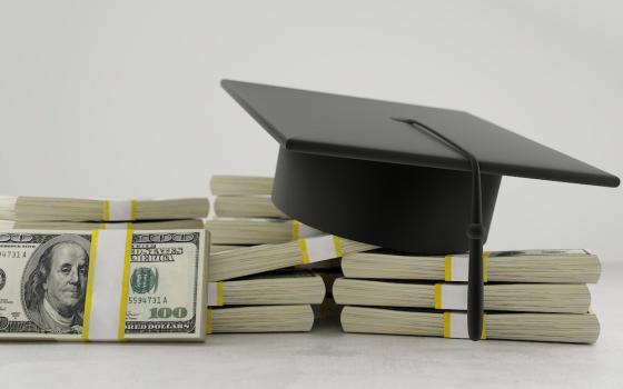 A college mortarboard hat resting on bundles of 100 dollar bills