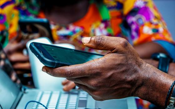 A man holds a cellphone in Lagos, Nigeria. (Unsplash/Olumide Bamgbelu)