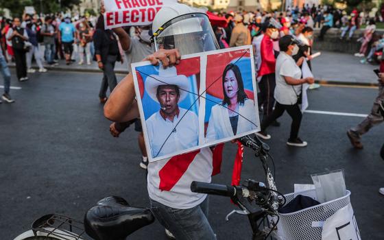 A protester in Lima, Peru, on April 17 holds a sign showing crossed out images of candidates Pedro Castillo and Keiko Fujimori, who will face each other in the second round of Peru's presidential election on June 6. (Newscom/Reuters/Sebastian Castaneda)