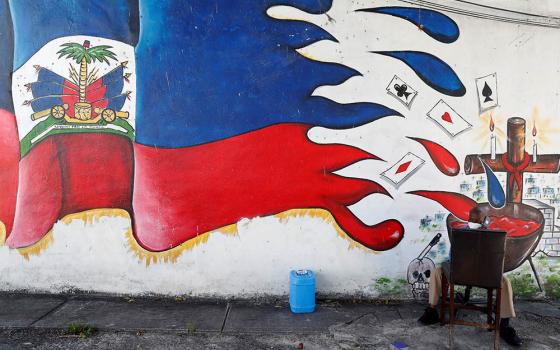 A man speaks on a phone next to a mural in the Little Haiti neighborhood of Miami July 8. (Newscom/Reuters/Shannon Stapleton)