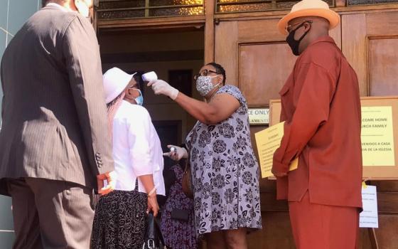 Ganine Arnold takes a visitor’s temperature outside Holy Name of Jesus Church in Los Angeles. (Courtesy of Fr. Kenneth Ugwu)