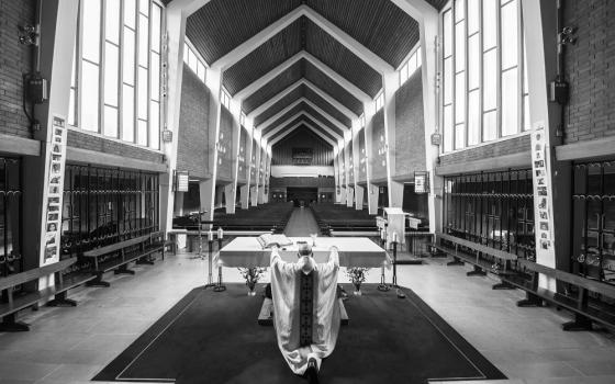 A priest kneels in front of the altar of an empty Holy Apostles Catholic Church in London Nov. 18, 2020. (CNS/Courtesy of Conference of Catholic Bishops of England & Wales/Marcin Mazur)