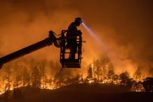 The Glass Fire burns in Calistoga, California, Sept. 28, as an employee of CableCom installs fiber optic cable. (CNS/Adrees Latif, Reuters)