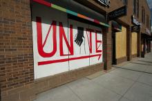 A white sign with clasped hands and the word UNITE in red on the side of a building (Unsplash/Priscilla Gyamfi)