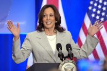 Harris raises hands, smiling, as she speaks at a lectern. 