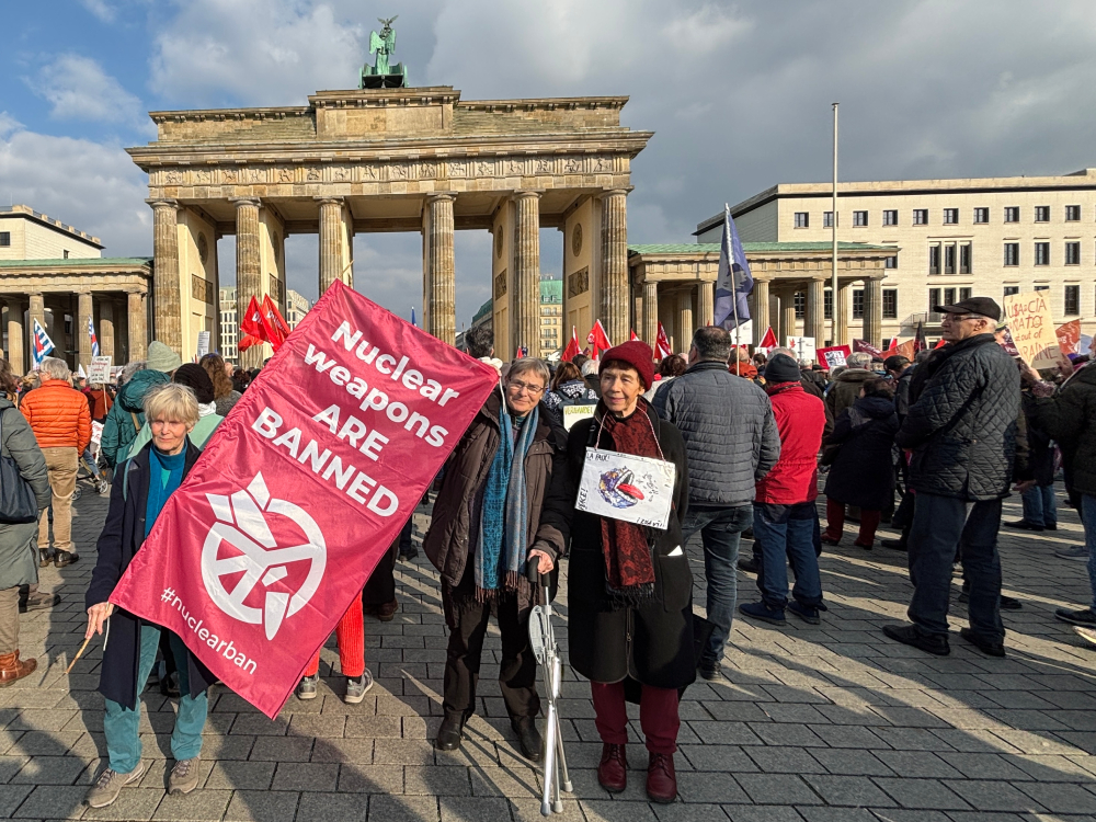 (From left to right) ICAN members Iris Buehrmann, Johanna Erdmann and Barbara Fuchs stand in front of Brandenburg Gate on March 15, protesting against an increase in Germany’s defense spending.