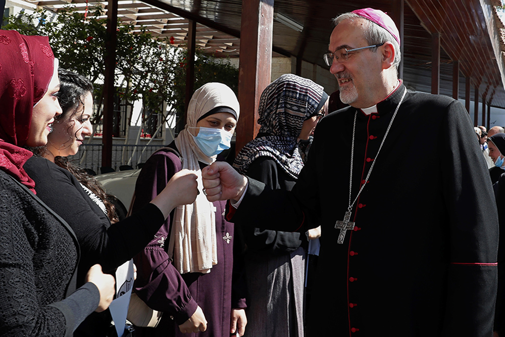 Latin Patriarch of Jerusalem Pierbattista Pizzaballa fist bumps as he is greeted on arrival to the Rosary Sisters School, which was damaged last month during an 11-day war between Israel and the Hamas militant group that rules Gaza, in Gaza City, Monday, June 14, 2021. (AP Photo/Adel Hana, File)