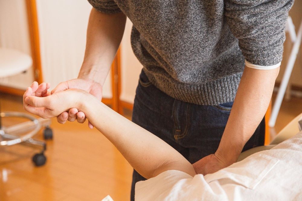 Physical therapist moves patient's arm.