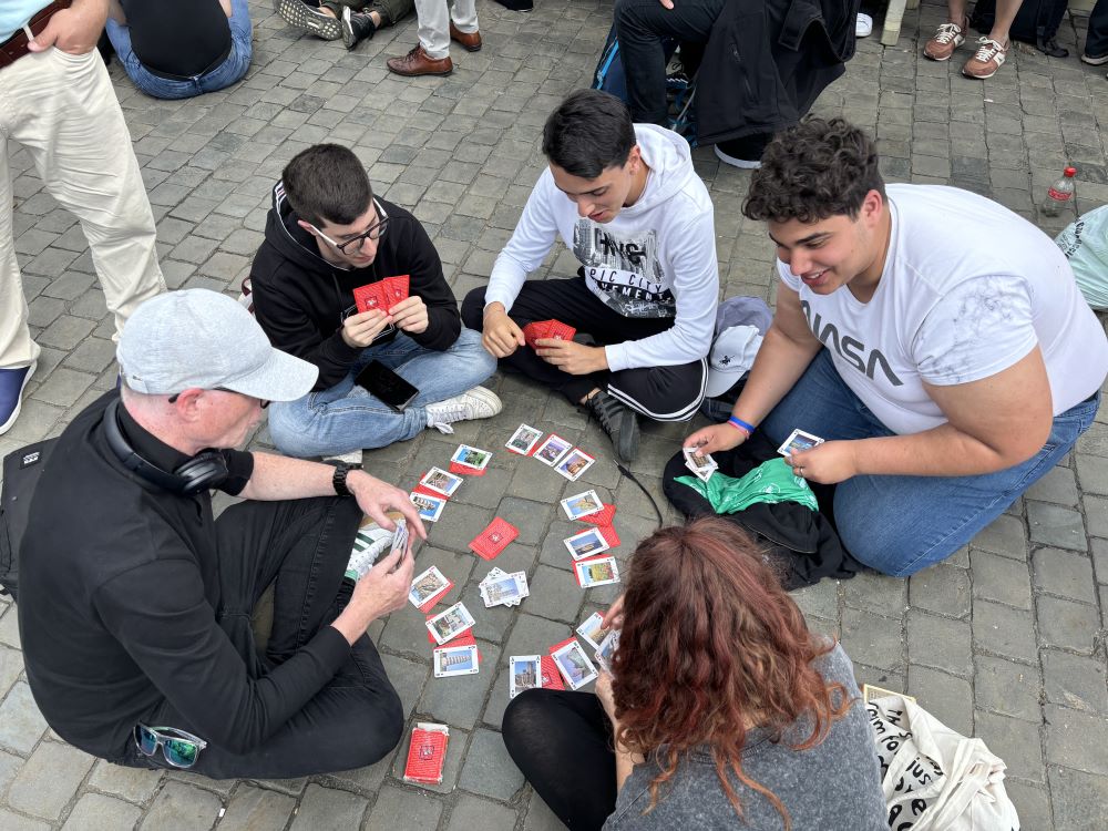 A group of Italian teens leaned against each other and napped while awaiting smoke from the Sistine Chapel May 8 until a man nearby offered to teach them a card game. Black smoke, indicating the cardinals had not yet chosen a new pope, flowed from the chimney on the Sistine Chapel at 11:51 a.m. Rome time. (NCR photo/Olivia Bardo)