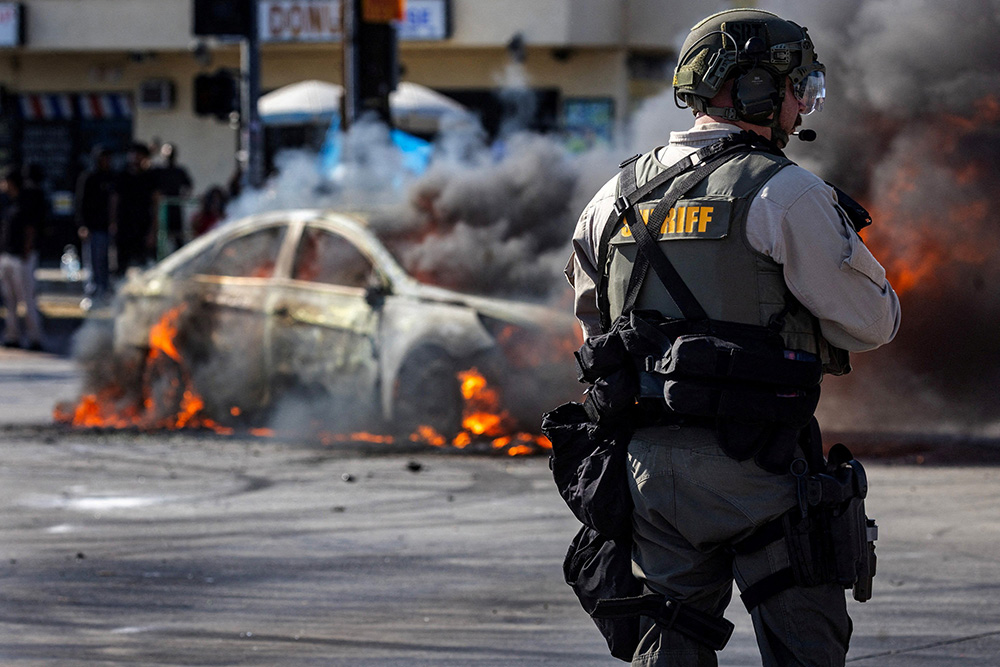 Smoke rises from a burning car on Atlantic Boulevard during a standoff by protesters and law enforcement, following multiple detentions by U.S. Immigration and Customs Enforcement in Compton, Calif., June 7, 2025. (OSV News/Reuters/Barbara Davidson)