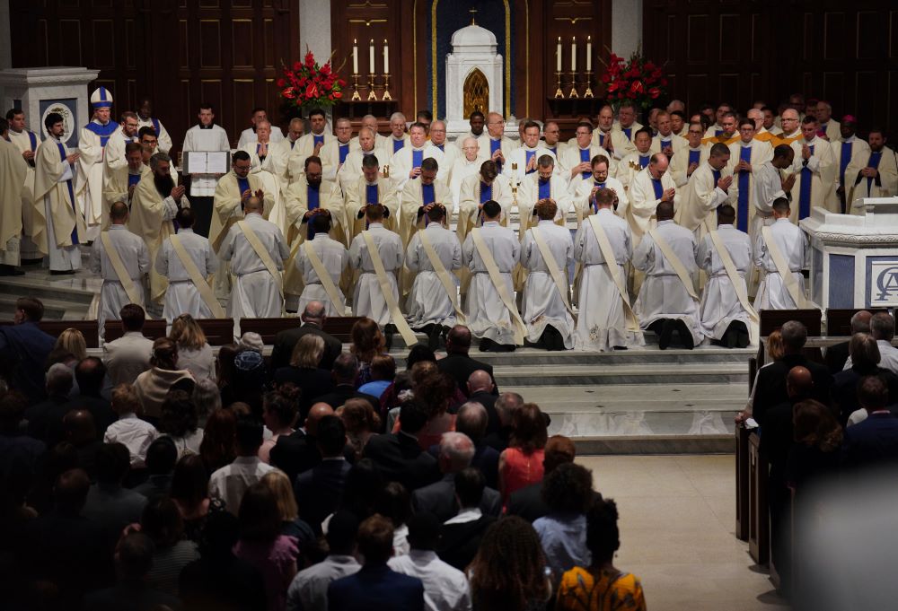 Priests and bishops bless the 12 newly ordained priests during Mass at the Cathedral of St.  Thomas More in Arlington, Va., on June 7. (AP/Jessie Wardarski)