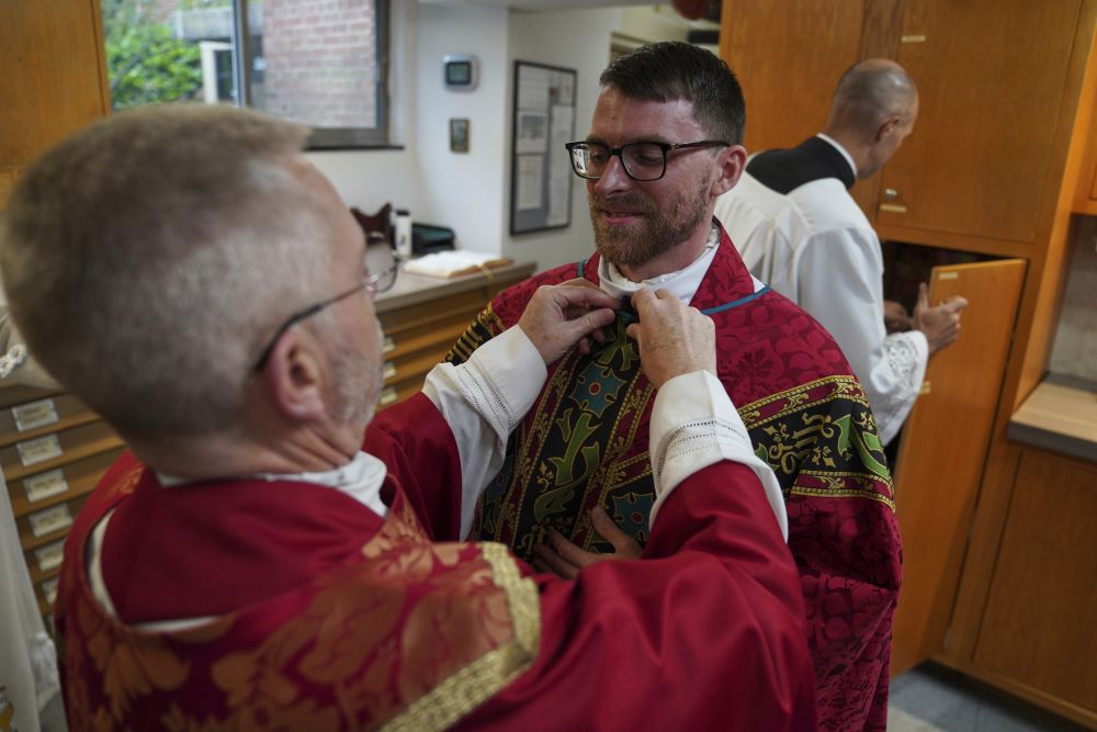 Fr. Donald Planty, left, assists Fr. Tim Banach with a microphone before Banach's first Mass at St. Charles Borromeo Catholic Church in Arlington, Va., on June 8. (AP/Jessie Wardarski)