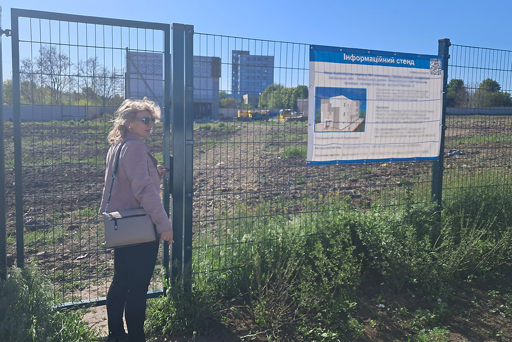 St. Don Bosco School principal Vitalia Vovk stands at the entrance to the site of a future school campus in Zaporizhzhia, in southern Ukraine (sign obscured for safety reasons). After two years of underground classes, Don Bosco's administrators started construction on a new school that will include both aboveground and belowground classroom space. (Marc Roscoe Loustau)