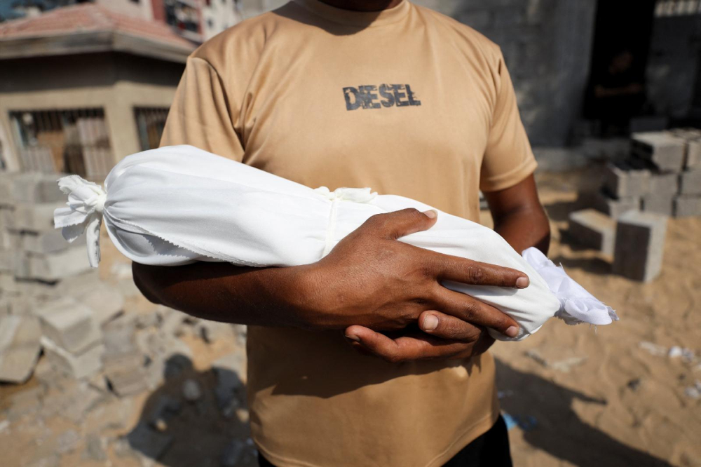 Adham carries the body of his nephew, 6-week-old Yousef al-Safadi, who died of starvation, according to health officials, in Gaza City July 22, 2025. For months, U.N. officials, aid groups and experts have warned that Palestinians in the Gaza Strip are on the brink of famine without formally declaring one. (OSV News/Khamis Al-Rifi/Reuters)