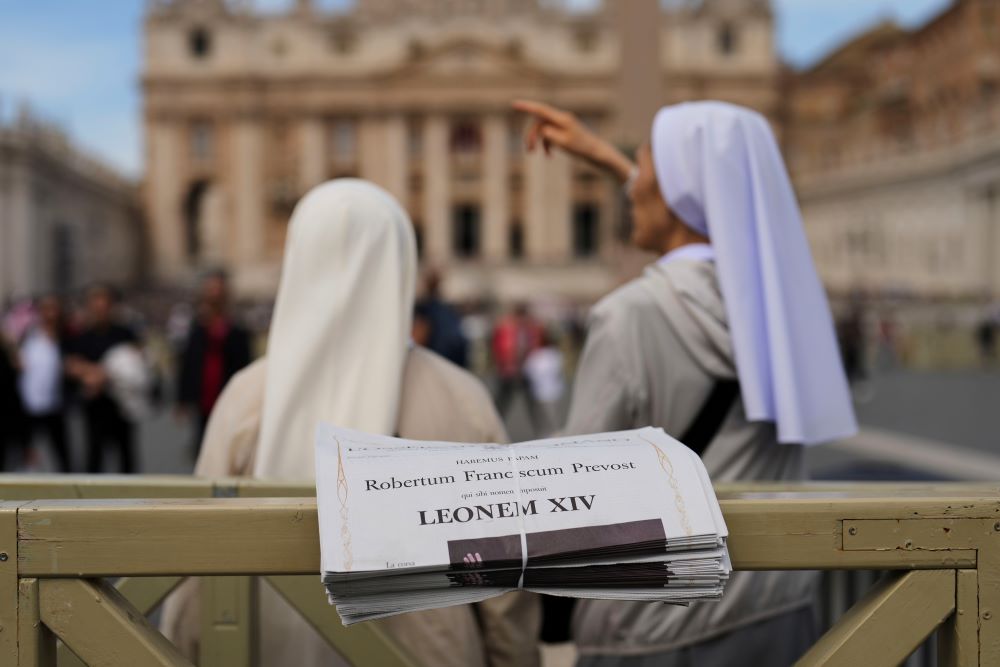 Nuns stand next to copies of L'Osservatore Romano, a Vatican newspaper, with headlines about Pope Leo XIV.