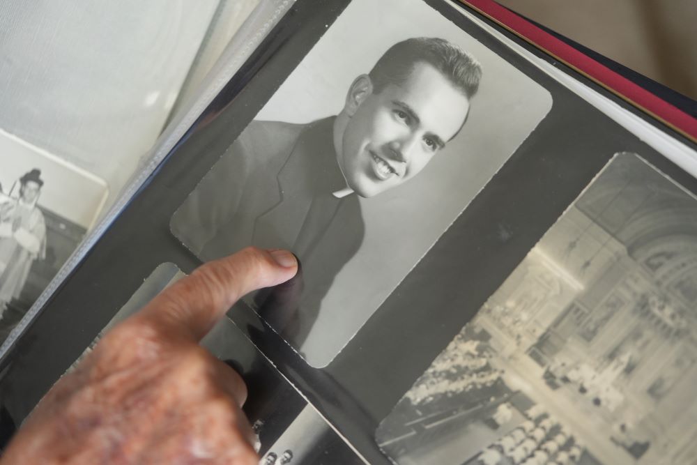 Fr. James Kelly points to a portrait of himself as a young priest in his photo album.
