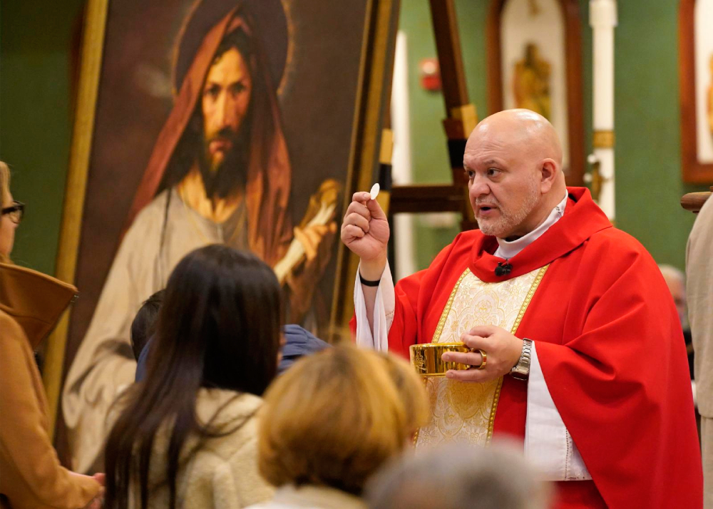 Father Carlos Martins, a member of the Companions of the Cross religious community, distributes Communion during a special Mass celebrated in honor of St. Jude the Apostle at St. Jude Church in Mastic Beach, N.Y., Nov. 27, 2023. Father Martins, a well-known exorcist and co-host of "The Exorcist Files" podcast, has been cleared of charges stemming from a relic exposition held in November 2024 at a parish in Joliet, Ill. (OSV News/Gregory A. Shemitz)