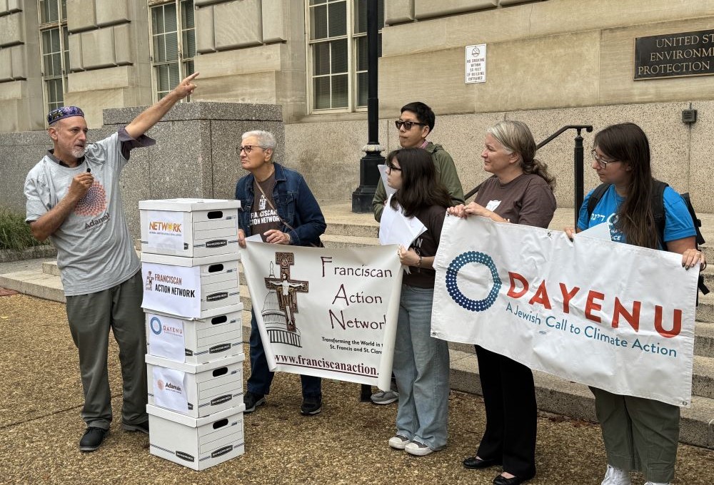People stand with banners in front of EPA building. 