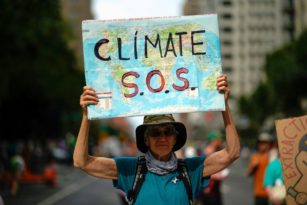 A man holds a sign reading "Climate SOS" during a demonstration.