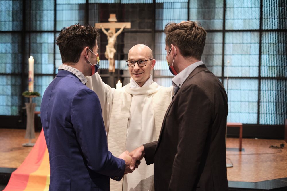 A priest blesses a gay couple. 