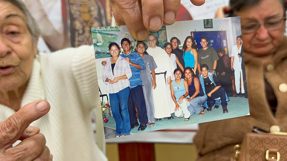 Socorro Cassaro holds up a picture of Augustinian Fr. Robert Prevost with a group of young people at Our Lady of Montserrat Parish in Trujillo, Peru. Prevost, the future Pope Leo XIV, served as parochial administrator of the parish from 1992 to 1999. (NCR photo/Justin McLellan)