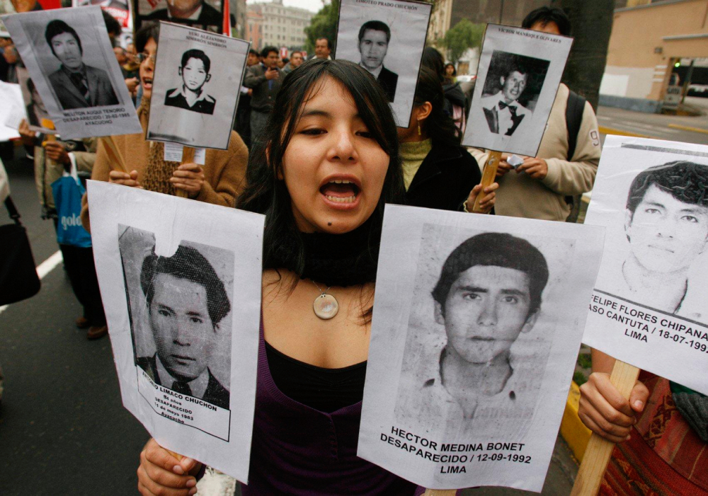 During a march in Lima, Peru, Sept. 27, 2007, a woman carries pictures of people murdered during the term of former Peruvian President Alberto Fujimori. Chile extradited Fujimori Sept. 22, 2007, paving the way for a trial in Peru. (CNS/Reuters/Pilar Olivares)