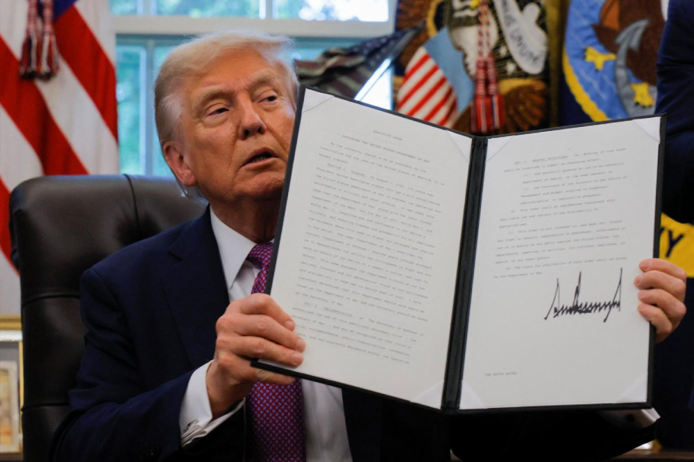 U.S. President Donald Trump holds up an executive order he signed to rename the Department of Defense the "Department of War," accompanied by U.S. Defense Secretary Pete Hegseth, in the Oval Office of the White House in Washington Sept. 5, 2025. (OSV News/Reuters/Brian Snyder)