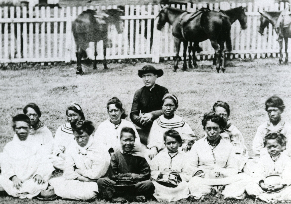 St. Damien de Veuster is pictured with young people at the settlement for those with Hansen's disease, or leprosy, on the Hawaiian island of Molokai. (CNS)