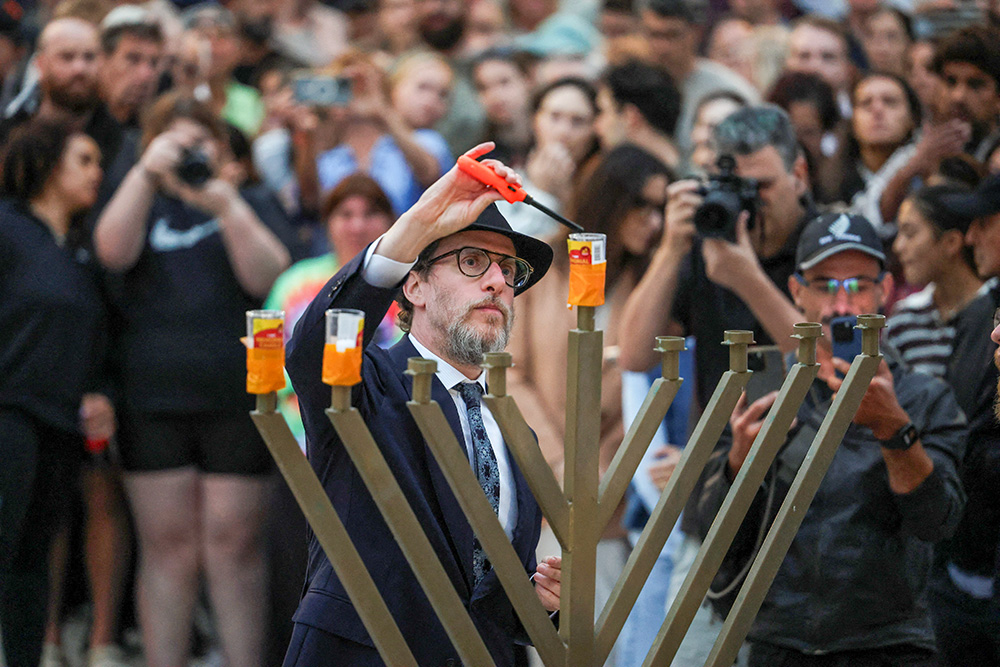 Rabbi Levi Wolff lights a menorah as people pay respects at Bondi Pavilion Dec. 15, 2025, to victims of a shooting during a Jewish holiday celebration at the beach in Sydney. (OSV News/Reuters/Hollie Adams)