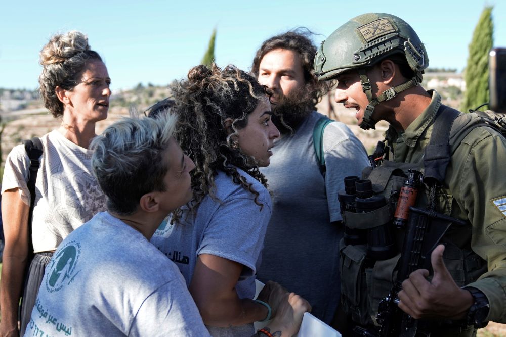 Israeli activists surround Alice Kisiya, center, as they try to enter her family's land, after the Palestinian family was forcefully evicted by Israeli settlers backed by soldiers who declared it a closed military area, in the West Bank town of Beit Jala Aug. 2, 2024. (AP/Mahmoud Illean)