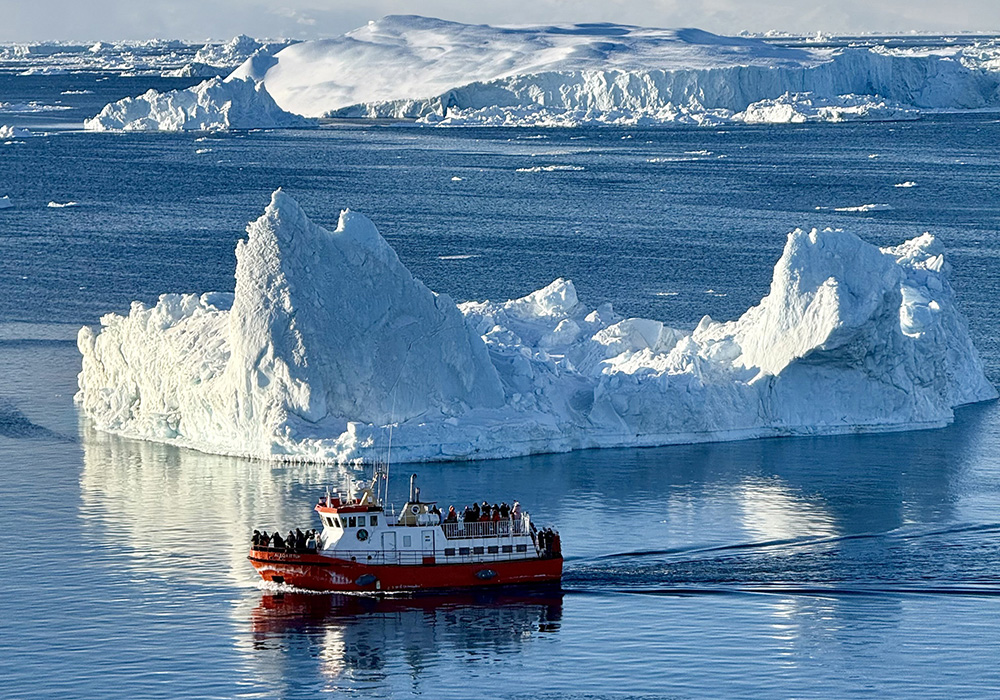 A boat navigates around a portion of an iceberg near Nuuk, Greenland, in this undated photo provided by Fr. Tomaž Majcen, a Conventual Franciscan, and the only Catholic parish priest serving in Greenland. Majcen says talks about a U.S. takeover are being met with concern, fear and "a quiet strength" by residents. (OSV News/Fr. Tomaž Majcen)