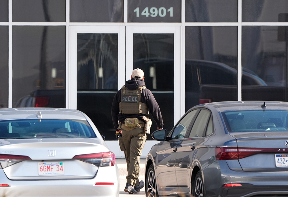 An ICE agent stands outside a warehouse as federal officials tour the facility to consider repurposing it as an ICE detention facility, Jan. 15, 2026, in Kansas City, Missouri. (AP photo/Charlie Riedel)