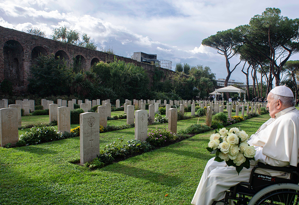 Pope Francis holds a bouquet of white roses as he visits the graves of members of Commonwealth military units who died during and immediately after World War II and now rest in the Rome War Cemetery where the pope celebrated Mass Nov. 2, 2023, the feast of All Souls. (CNS/Vatican Media)