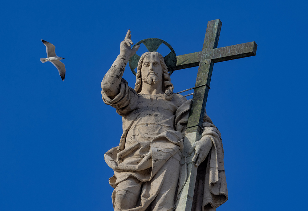 A bird flies over the statue of the Risen Christ on top of the facade of St. Peter's Basilica at the Vatican during Pope Francis' weekly general audience Nov. 13, 2024. (CNS/Pablo Esparza)
