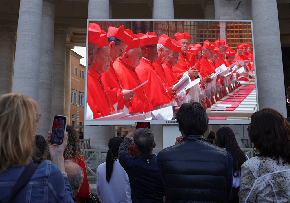People watch a screen in St. Peter's Square at the Vatican as cardinals from around the world gather in the Sistine Chapel May 7, 2025, on the first day of the conclave to elect the next pope. (OSV News/Reuters/Amanda Perobelli)