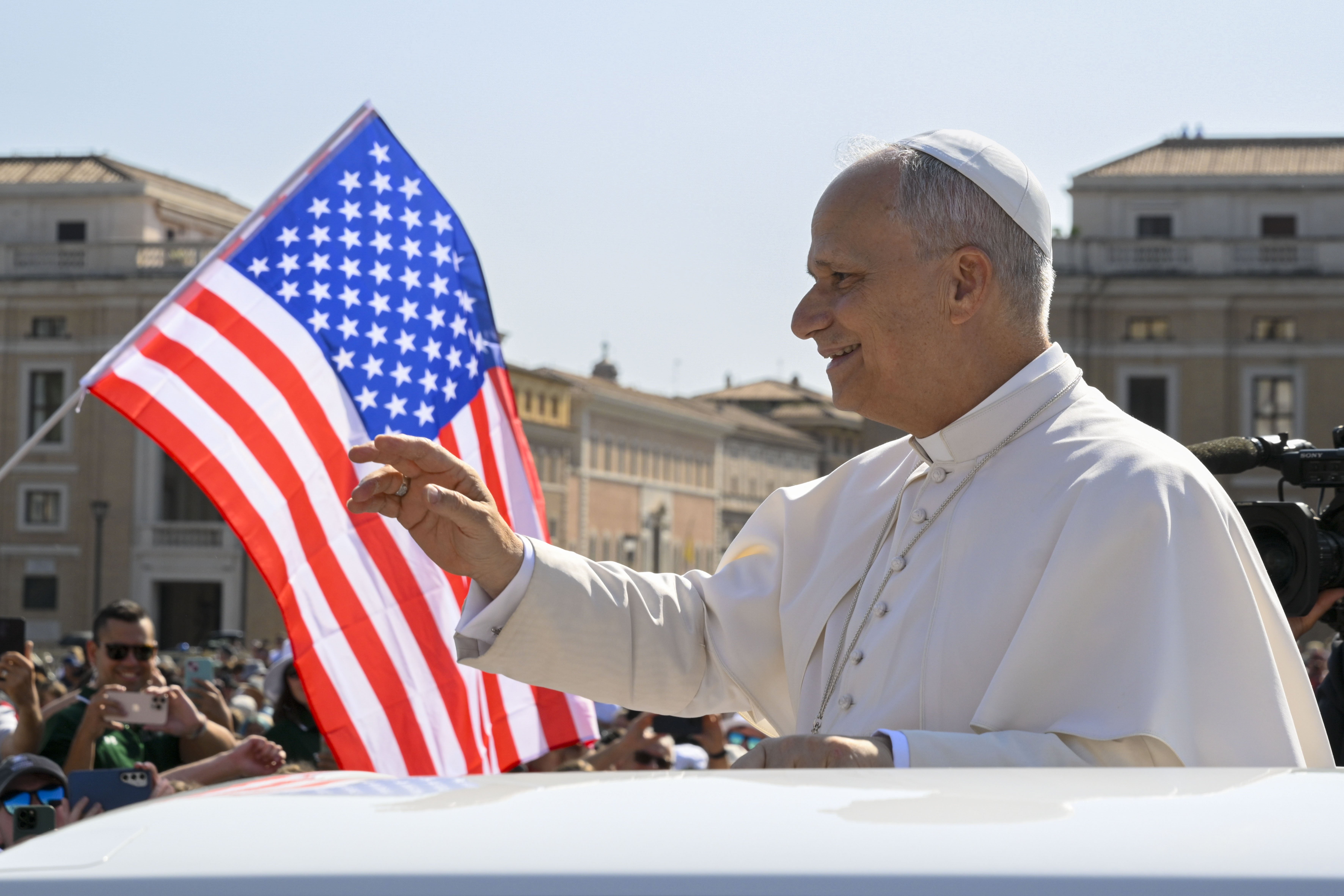 With a U.S. flag in the background, Pope Leo XIV waves to the crowd from the popemobile as he rides around St. Peter's Square at the Vatican before his weekly general audience Aug. 6, 2025. Pope Leo named Archbishop Caccia as the new papal nuncio to the United States March 7, 2026. He succeeds Cardinal Christophe Pierre, who turned 80 in January and had served in the post since 2016. (CNS photo/Vatican Media)