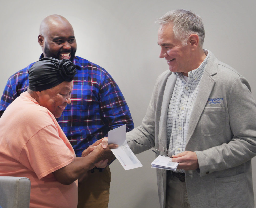 Chad Eachern, president and CEO of Edmundite Missions, presents a check to Eloise Ravioree Feb. 27, 2026, who is participating in the Selma, Ala.-based Catholic social services agency's farming initiative that helps support small farmers in the South's impoverished Black Belt region. Smiling in back is Olandous Curry, senior agriculture director for the Edmundite Missions' Rural Economic Development Center. (OSV News photo/courtesy Edmundite Missions)