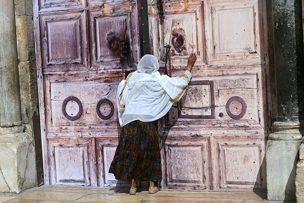 An Ethiopian Christian woman prays at the locked doors of the Church of the Holy Sepulcher in the Old City of Jerusalem March 4, 2026, on day five of the U.S.-Israel war with Iran. The church and other religious sites as well as stores were locked shut by order of the Israeli government as Iranian ballistic missiles were fired at Israel. (OSV News/Debbie Hill)