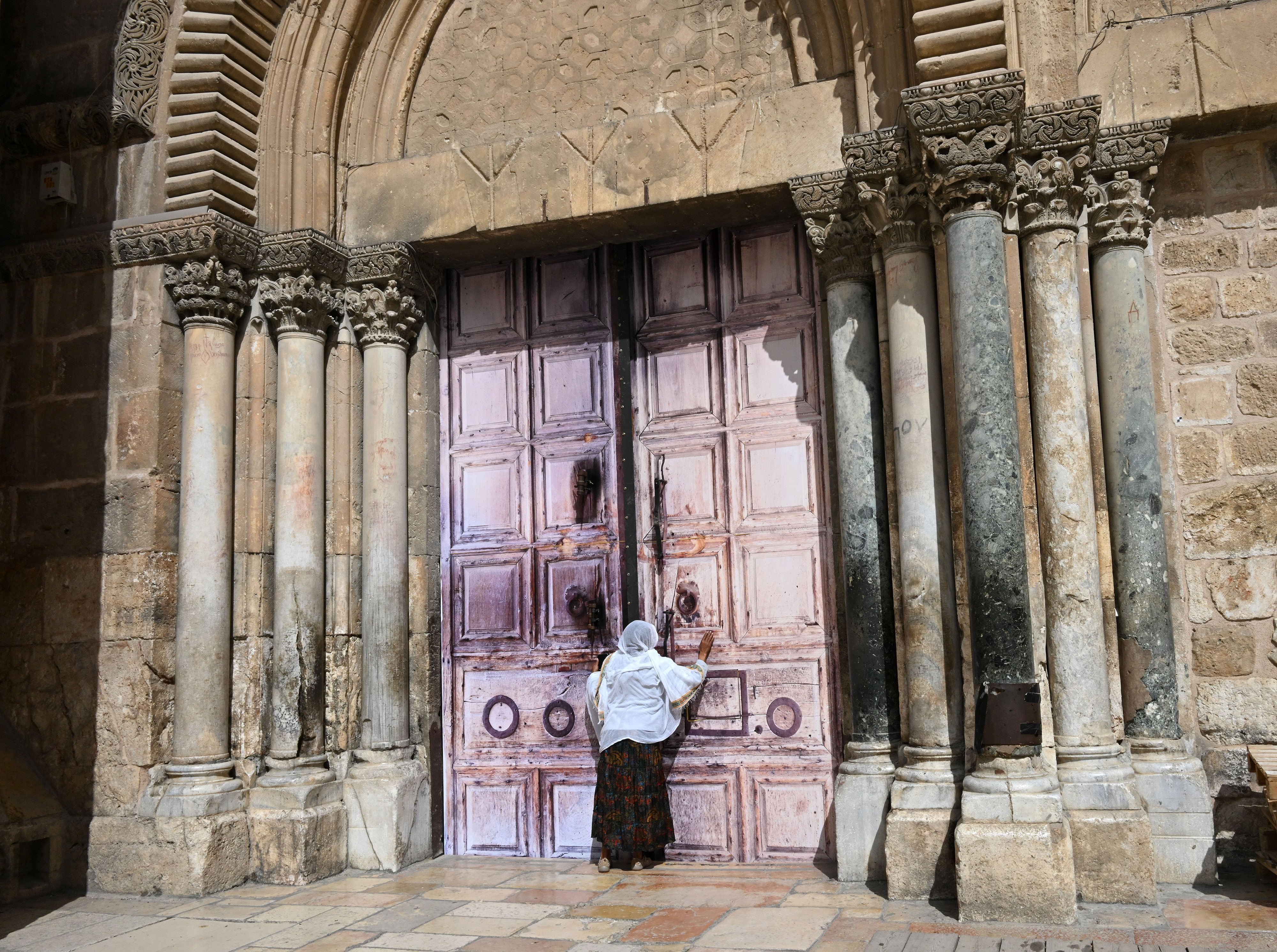 An Ethiopian Christian woman prays before the closed doors of the Church of the Holy Sepulchre in the Old City of Jerusalem on March 4, 2026, the fifth day of the war between the United States and Israel against Iran. 