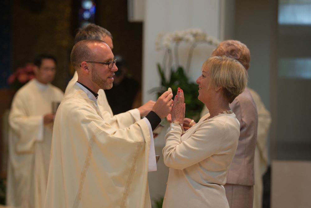 Jesuit Fr. Patrick Gilger gives his mother, Kristin Grady Gilger, Communion for the first time. (Courtesy of Gilger family)