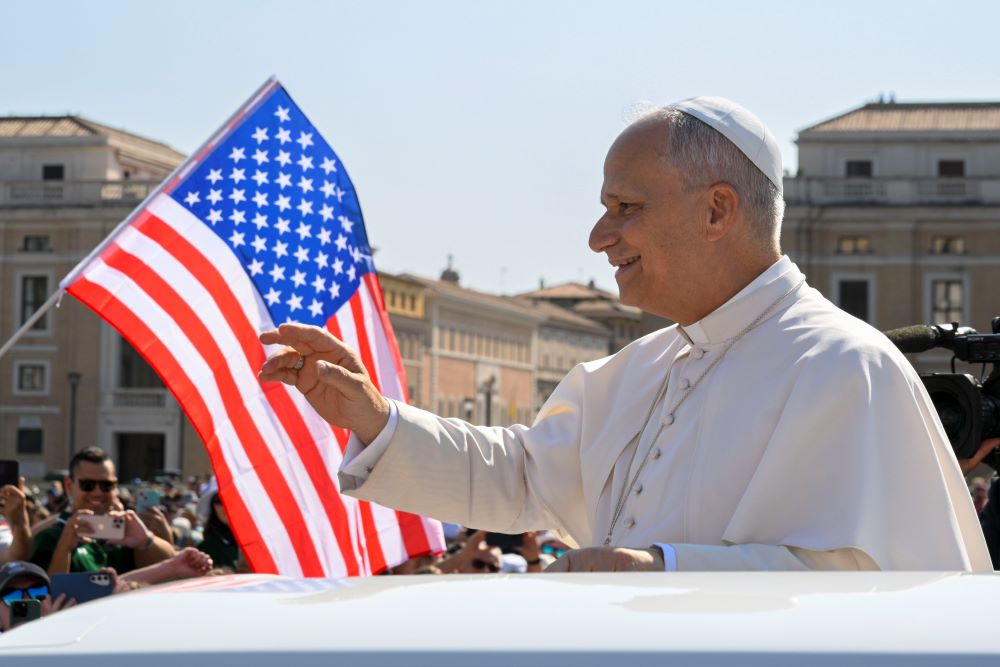 With a U.S. flag in the background, Pope Leo XIV waves to the crowd from the popemobile as he rides around St. Peter's Square at the Vatican before his weekly general audience Aug. 6, 2025. (CNS/Vatican Media)
