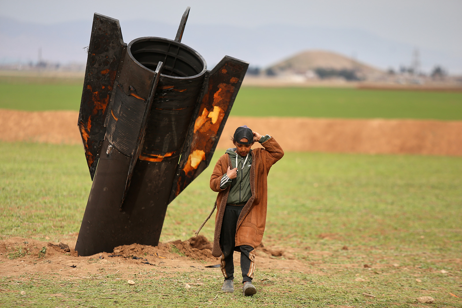 A shepherd boy walks away from an unexploded Iranian projectile that landed in an open field in the outskirts of Qamishli, eastern Syria, March 4, 2026. (RNS/AP/Baderkhan Ahmad)